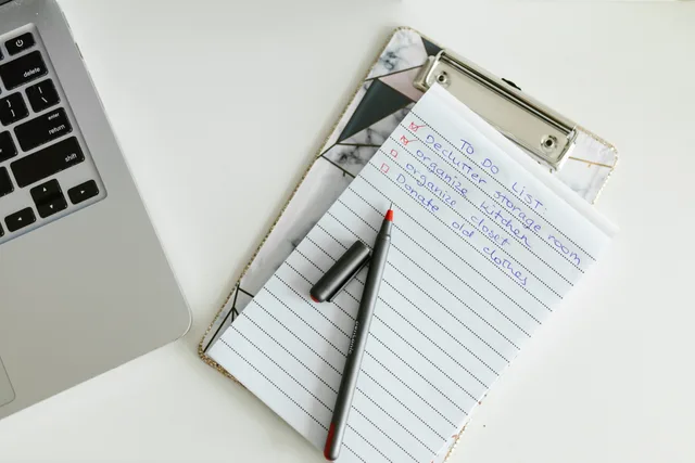 A neatly organized to-do list on a clipboard next to a laptop and pen, conveying productivity. Ansættelseskontrakten: Sådan læser du dine vilkår