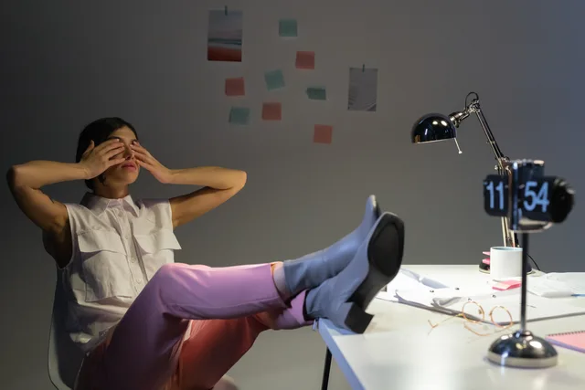 Overworked woman takes a break at her desk, showing exhaustion and relaxation. Hviletid og pauser: Hvad kræver arbejdsmiljøloven?